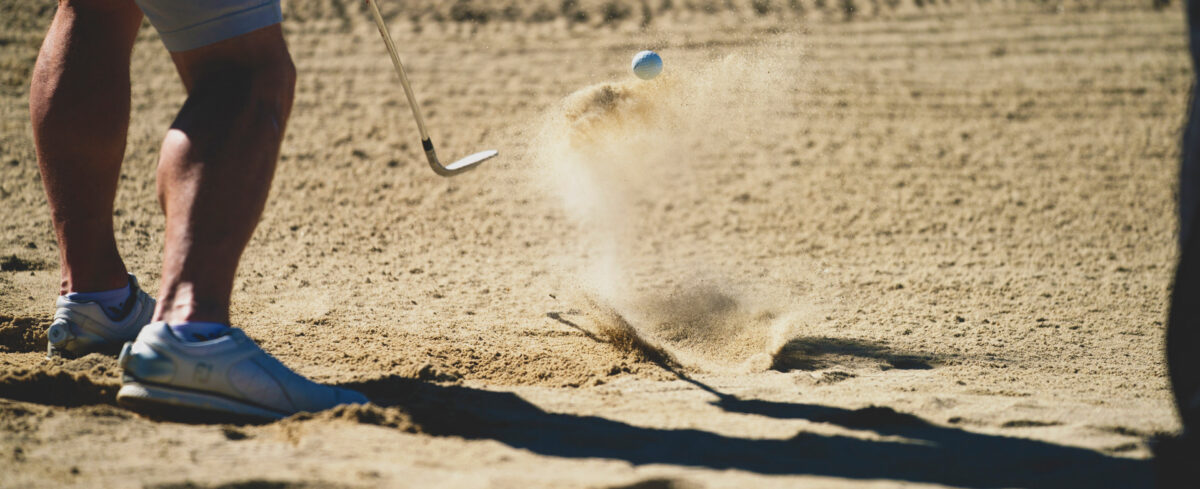 Golfer hitting a ball out of a sand bunker