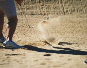 Golfer hitting a ball out of a sand bunker